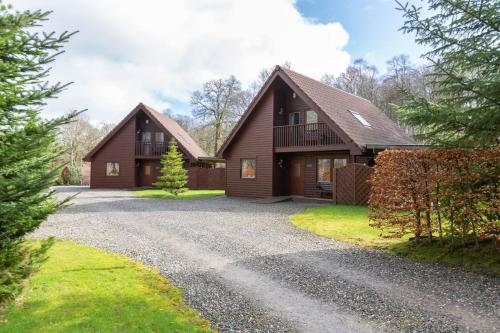 a home on a gravel driveway at Loch Lomond Luxury Lodges in Drymen