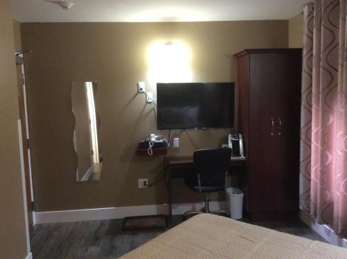 a room with a desk with a computer and a television at Villegiature Deux Rivieres Resort in Tracadie