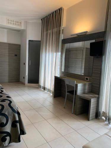 a bedroom with a desk and a bed and a television at Hotel Flamingo in Rimini