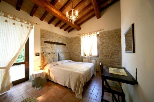 a bedroom with a bed and a table and windows at Agriturismo Borgo San Benedetto in Pietralunga