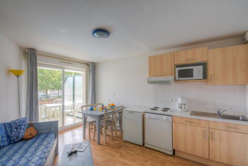 a kitchen with a couch and a table in a room at Vacancéole - Les Jardins de l'Amirauté in Les Sables-dʼOlonne