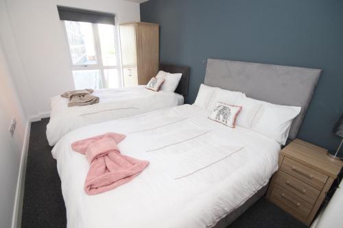 two beds with white sheets and a pink towel on them at Fox Street Delight in Liverpool