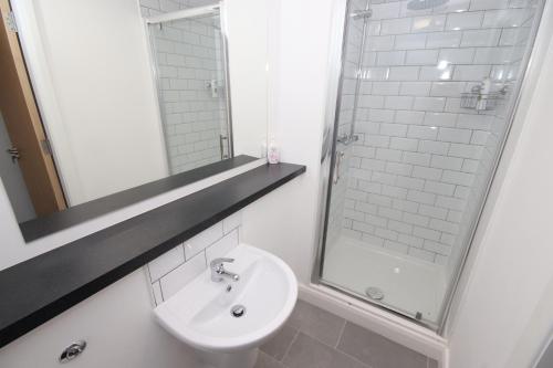 a white bathroom with a sink and a shower at Fox Street Delight in Liverpool