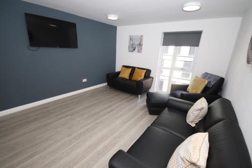 a living room with two black couches and a flat screen tv at Fox Street Delight in Liverpool