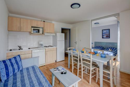 a kitchen and living room with a table and chairs at Vacancéole - Les Jardins de l'Amirauté in Les Sables-dʼOlonne