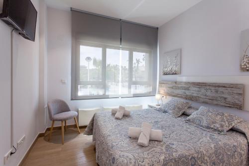 a bedroom with a bed with pillows and a window at ApartUP Patacona Beach Select in Valencia