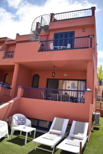 a pink building with chairs and tables in front of it at TC Bahía Meloneras in Meloneras