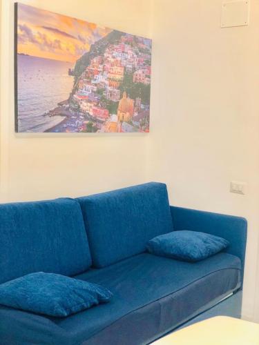a blue couch in a room with a painting on the wall at Penisola Home Experience in Vico Equense