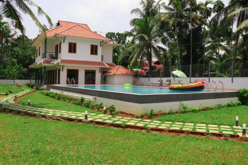 a house with a swimming pool in front of a house at Water's Edge Villas in Alleppey
