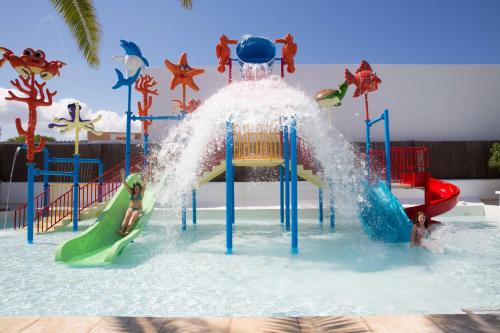 聖安東尼奧灣的住宿－Coral Star Hotel，游泳池里的水滑梯,人们在玩耍