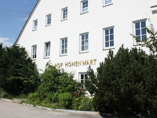 a white building with a sign on the side of it at Hotel Boarding House Hohenwart in Fuchstal