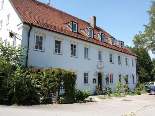 um grande edifício branco com um telhado vermelho em Hotel Boarding House Hohenwart em Fuchstal