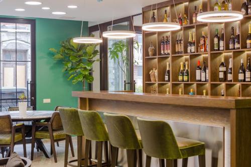 un restaurante con sillas verdes y un bar con botellas de vino en Hotel BLOOM Batumi, en Batumi