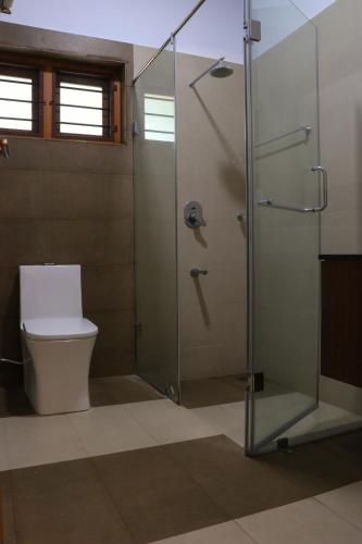 a bathroom with a glass shower with a toilet at Water's Edge Villas in Alleppey