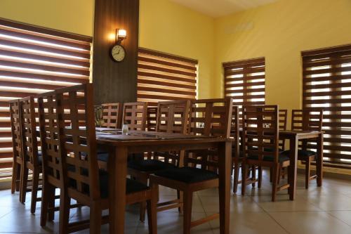 a dining room with a table and chairs and a clock at Water's Edge Villas in Alleppey