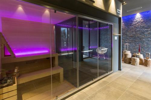 um chuveiro de vidro num quarto com iluminação roxa em Kepos Etna Relais & Exclusive Spa em Santa Venerina