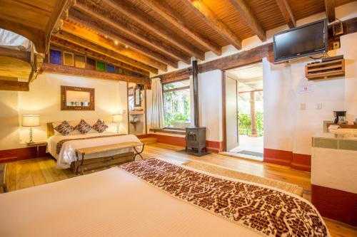 a bedroom with two beds and a tv in a room at Mesón De Leyendas Breakfast & Downtown in Valle de Bravo