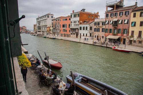 a group of people sitting at tables on a boat on a river at La Colombina in Venice