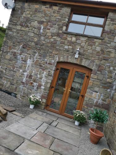 a stone building with a wooden door and potted plants at Cwm Farm Cwtch in Merthyr Tydfil