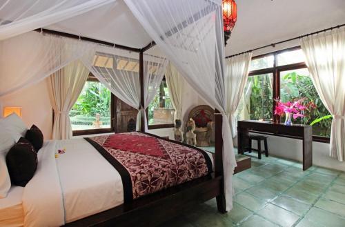 una camera da letto con letto a baldacchino e scrivania di Villa Jumah a Seminyak