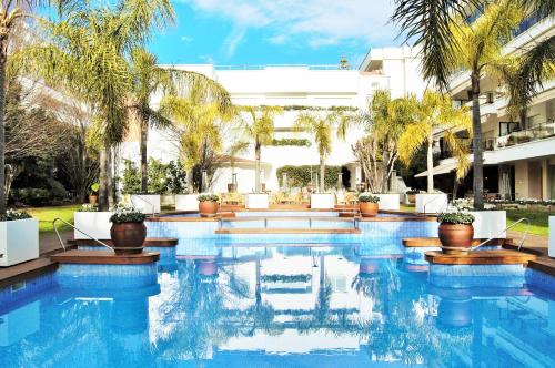 a swimming pool with palm trees and a building at Apartamento Sun Garden Lloret de Mar in Lloret de Mar