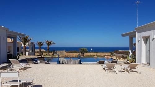 a patio with chairs and a pool and the ocean at CORALLI DEL PLEMMIRIO in Siracusa