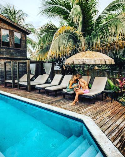 two people sitting on a deck next to a swimming pool at PUR Boutique Cabanas, Adults Only in San Pedro