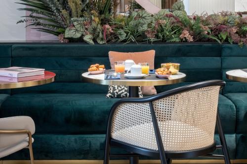 a table with food on it next to a green couch at Hôtel Parisianer in Paris