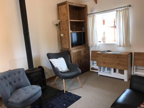 a living room with a chair and a desk and a television at Eviedale Cottages in Evie