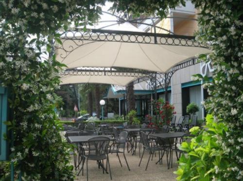 an outdoor patio with tables and chairs and an umbrella at Platani Hotel in Bolsena