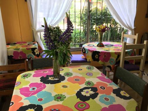 un comedor con dos mesas con flores. en Hospedaje Unelen en El Bolsón