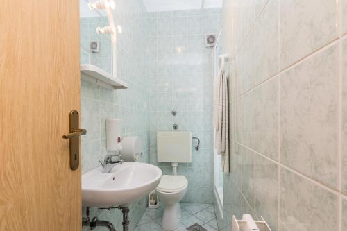 a white bathroom with a sink and a toilet at Apartmani Albi in Zaton