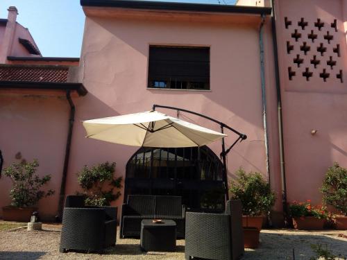 a pink building with a table and an umbrella at Residenza La Dimora ImPerfetta in Salionze