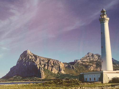 a lighthouse with a mountain in the background at La Dimora del Passante in San Vito lo Capo