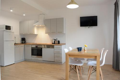 cocina con mesa de madera y electrodomésticos blancos en Apartamenty Asturia en Rymanów-Zdrój