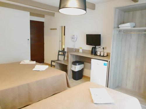 a room with two beds and a desk with a television at Hotel Olmuccio in Sainte-Lucie de Porto-Vecchio