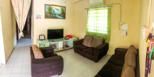 a living room with two chairs and a television at Homestay Villa Teluk Batik in Lumut