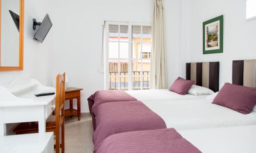 2 łóżka w pokoju z biurkiem i biurkiem w obiekcie Hotel Marbella w mieście Fuengirola