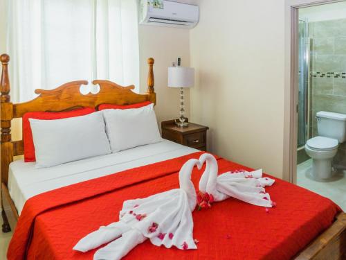 two swans dressed in white are sitting on a bed at Calliandras Apartment Complex in Kingstown