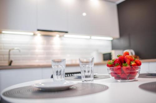 a table with two glasses and a bowl of strawberries at Apartament w Centrum II in Ustka