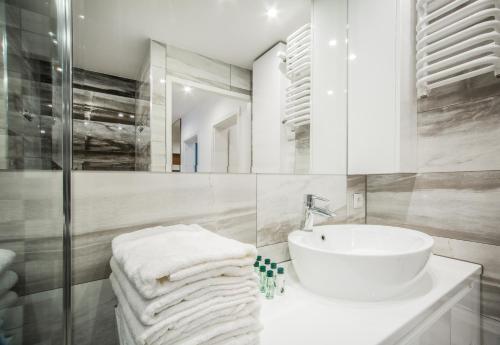 a white bathroom with a sink and a mirror at Apartament w Centrum II in Ustka