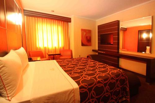 a hotel room with a bed and a television at Motel Mirage in Guadalajara