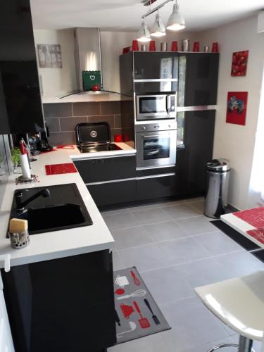 - une cuisine avec des armoires noires et un sol blanc dans l'établissement Les Marronniers, à Troyes