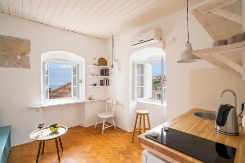 a kitchen with white walls and wooden floors and two windows at Central, Quiet & Romantic Apartment in Herceg-Novi
