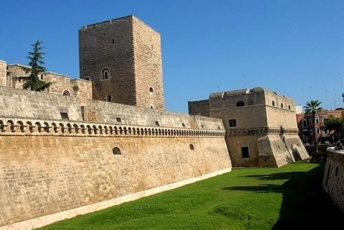 a large castle with a wall and green grass at Macario Apartment in the Old Town in Bari