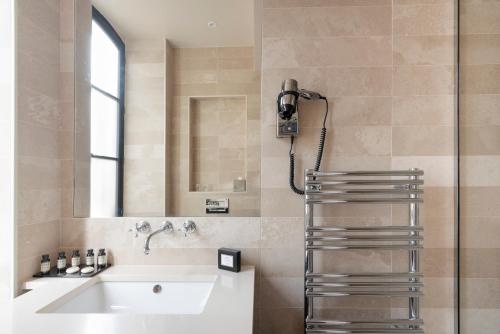 ein Bad mit einem Waschbecken und einer Dusche in der Unterkunft Hôtel Le Presbytère in Paris