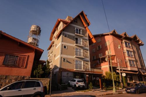 un edificio alto con coches estacionados frente a él en Alameda Alegra Hotel, en Gramado