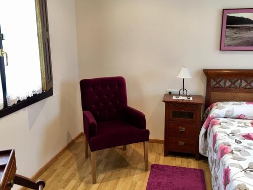 a bedroom with a chair and a bed and a desk at Hotel Rural El Texeu in Llanes
