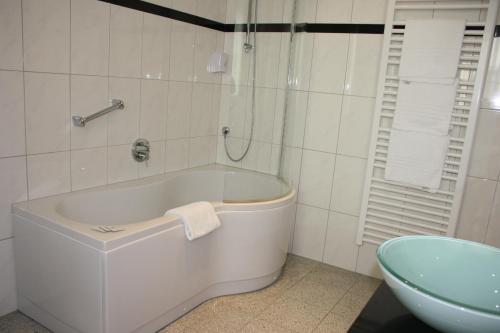 a white bath tub in a bathroom with a sink at Hotel Retterath am Nürburgring in Wiesemscheid