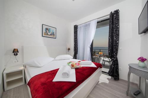 a bedroom with a bed with a red blanket and a window at Villa Matić in Makarska